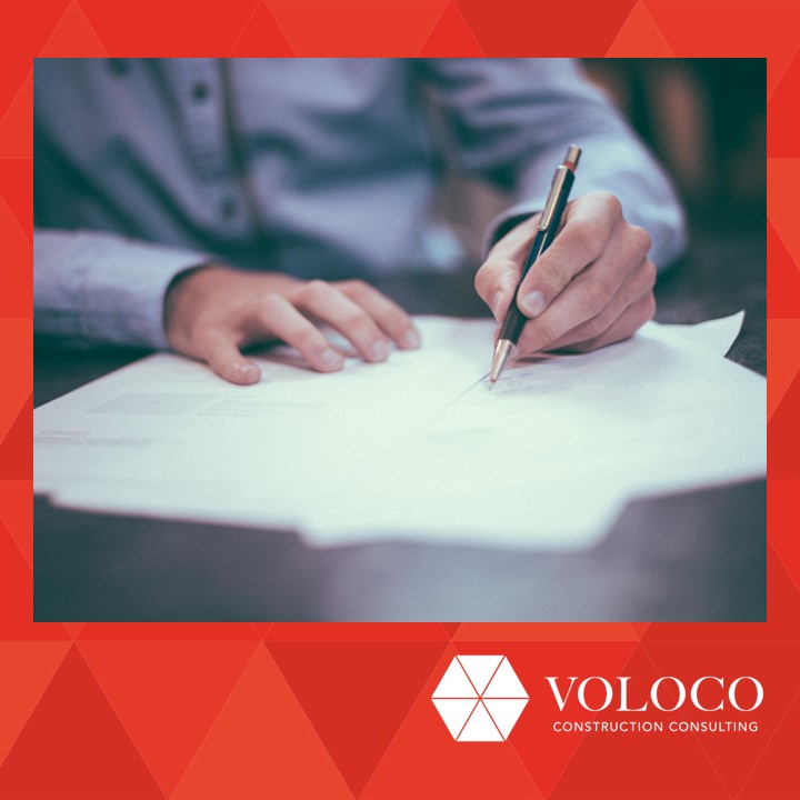 Person in blue shirt writing on papers at a table.